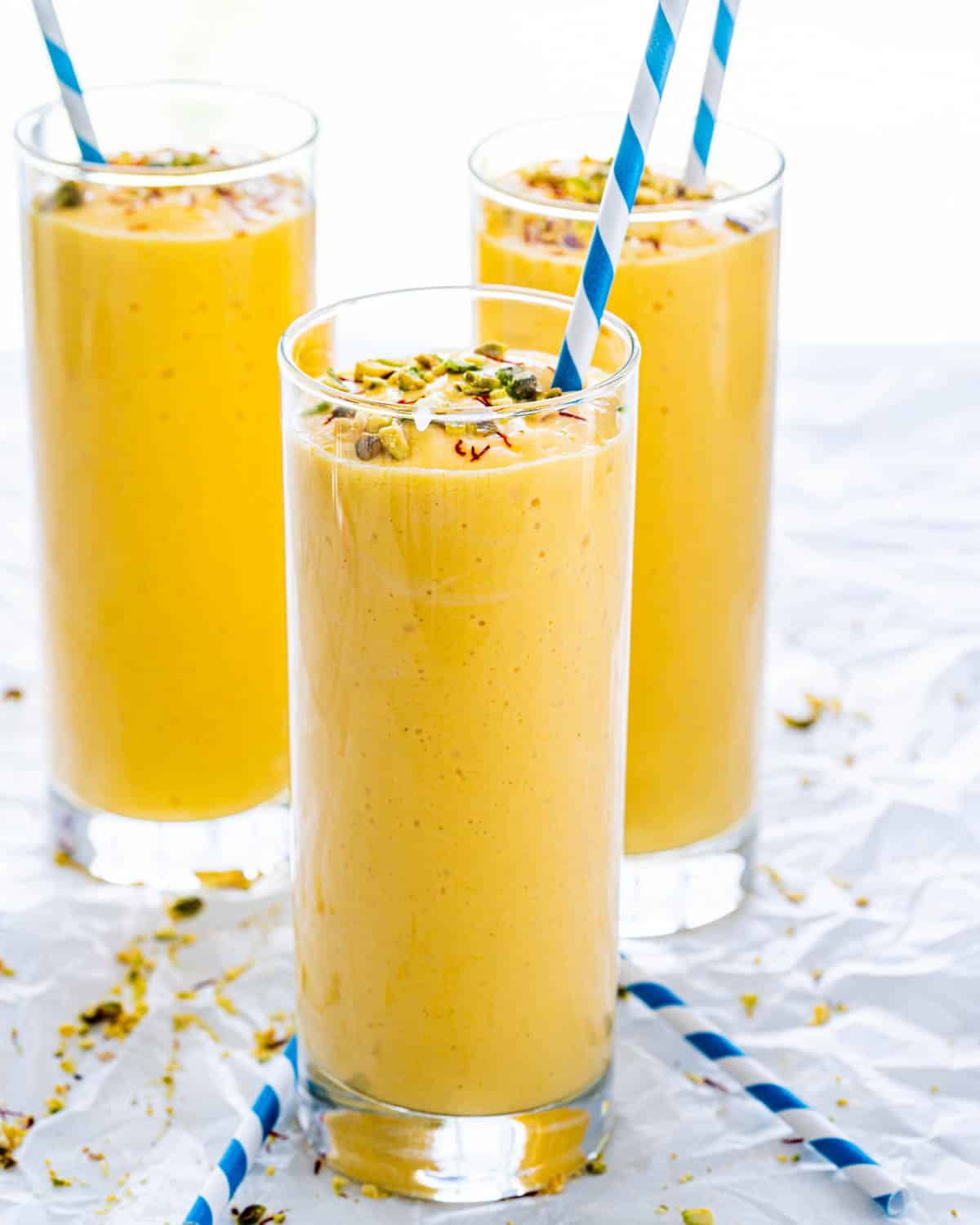 3 glasses of mango lassi garnished with pistachios