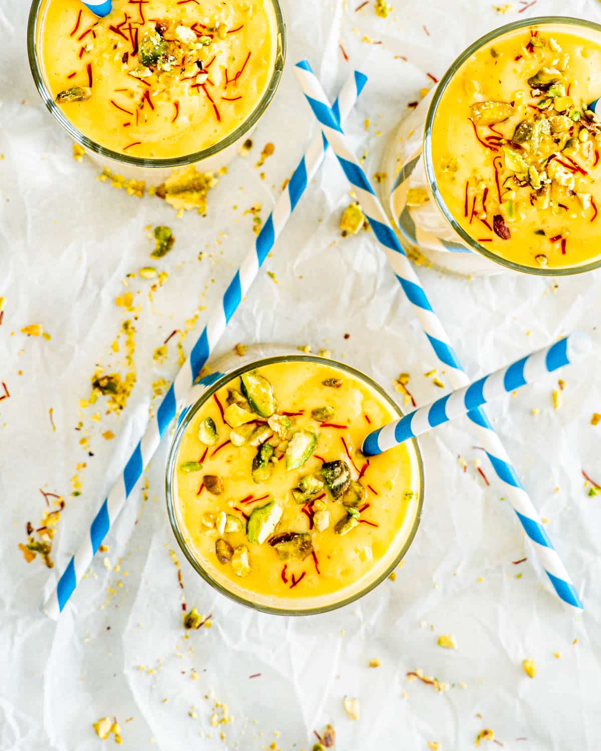 overhead shot of 3 mango lassi garnished with pistachios