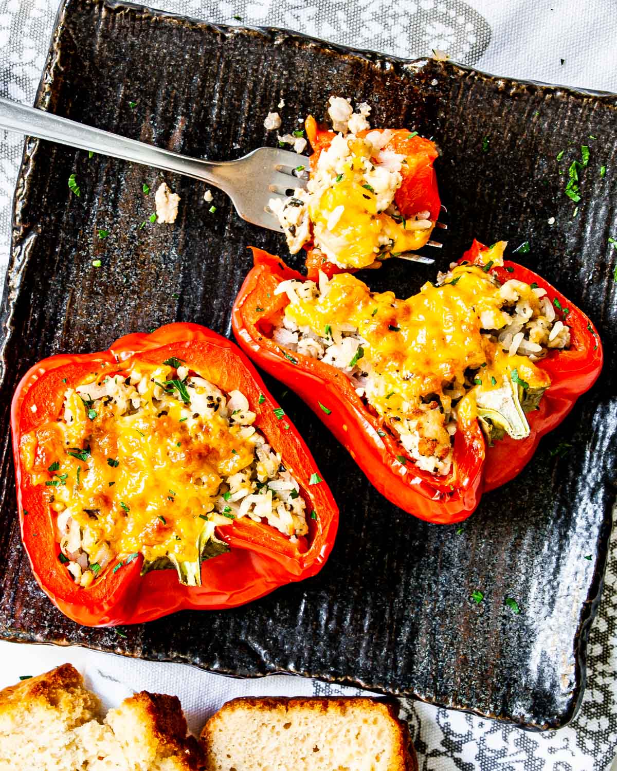 overhead shot of two stuffed pepper halves on a black plate with a fork holding a bite