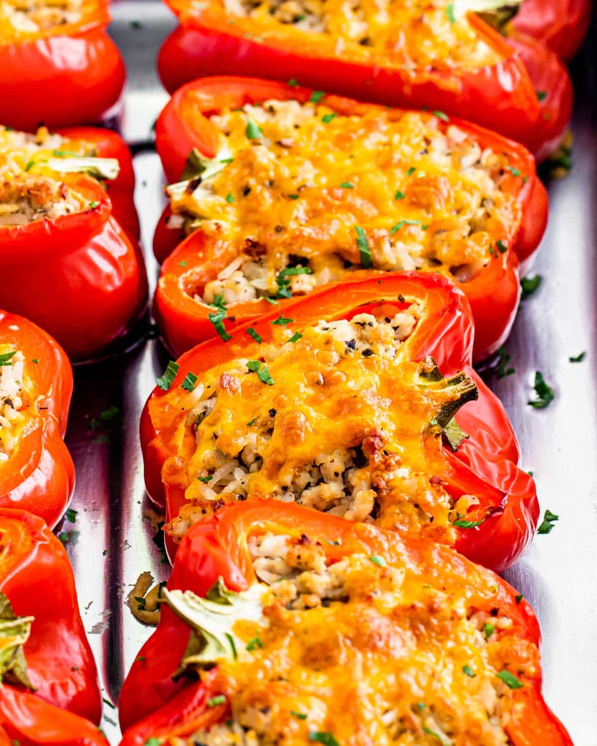 closeup sideview shot of skinny stuffed pepper halves topped with a bit of cheese in a baking dish