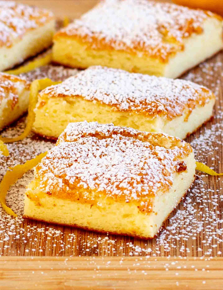 2 ingredient lemon bars sprinkled with powdered sugar on a cutting board.