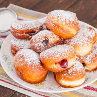 a plate of cherry filled donuts dusted with powdered sugar