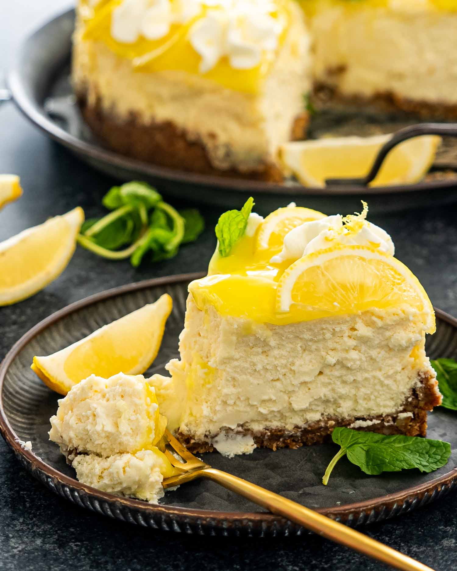 a slice of lemon cheesecake on a plate with a golden fork.