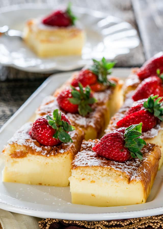 a plate with pieces of magic cake topped with strawberries