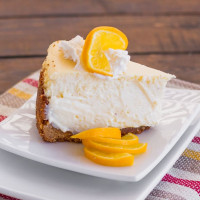 a slice of meyer lemon cheesecake garnished with meyer lemons