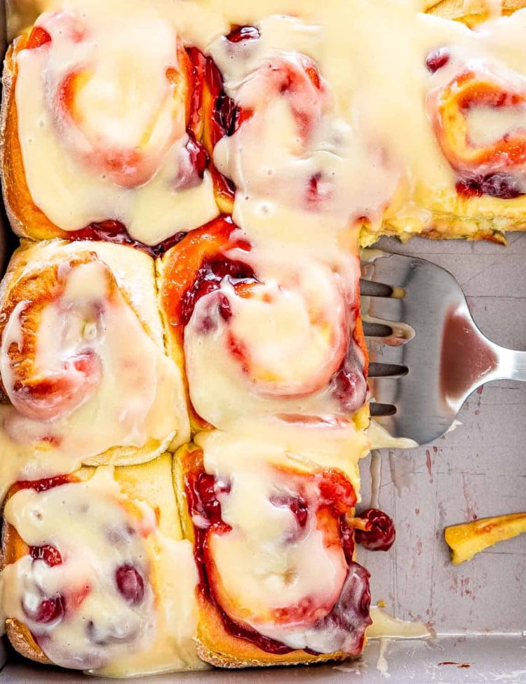 a spatula holding a cherry roll in a pan full of cherry rolls.