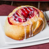 a cherry roll drizzled with icing on a plate