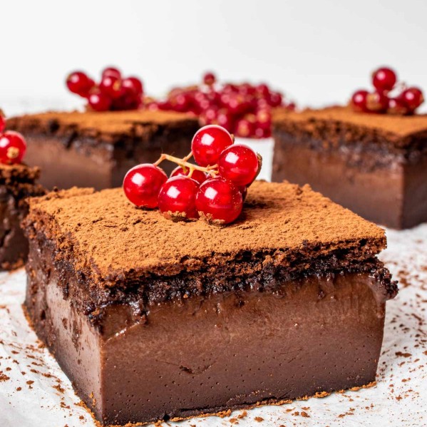 chocolate magic cake slices sprinkled with cocoa powder and garnished with garnish.