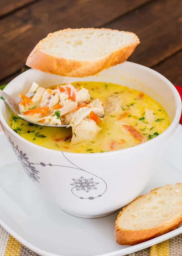 A bowl of Chicken Soup A La Grec with a slice of bread on the edge of the bowl