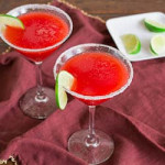 two strawberry margaritas in sugar rimmed martini glasses with lime wheels