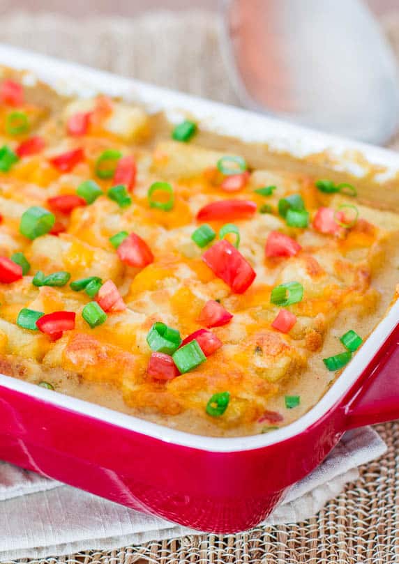 mexican tater topped casserole garnished with chopped tomato and green onion
