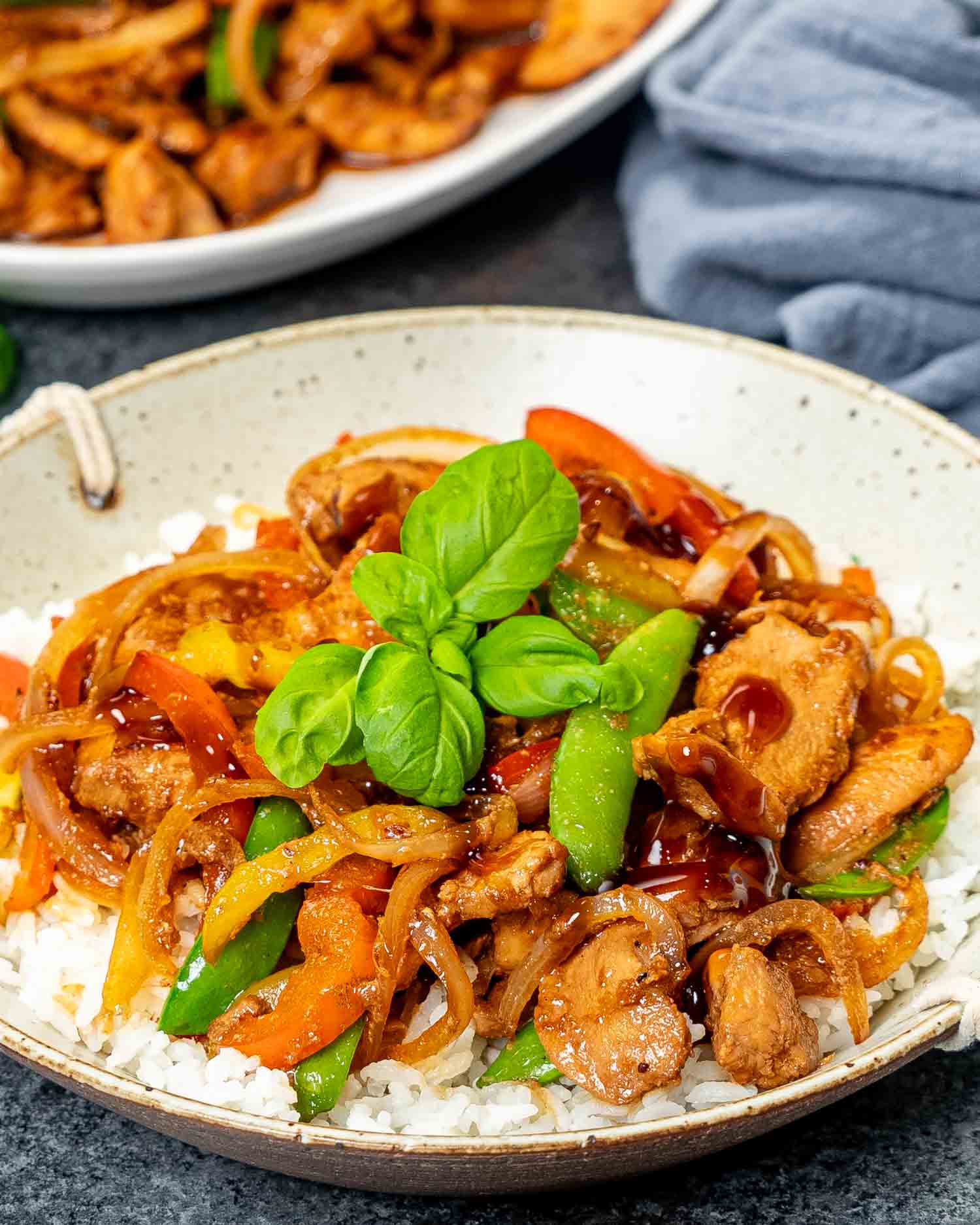 a serving of oyster sauce chicken over cooked white rice garnished with basil.