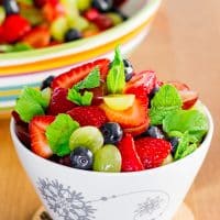 a bowl full of summer fruit salad with lemon dressing