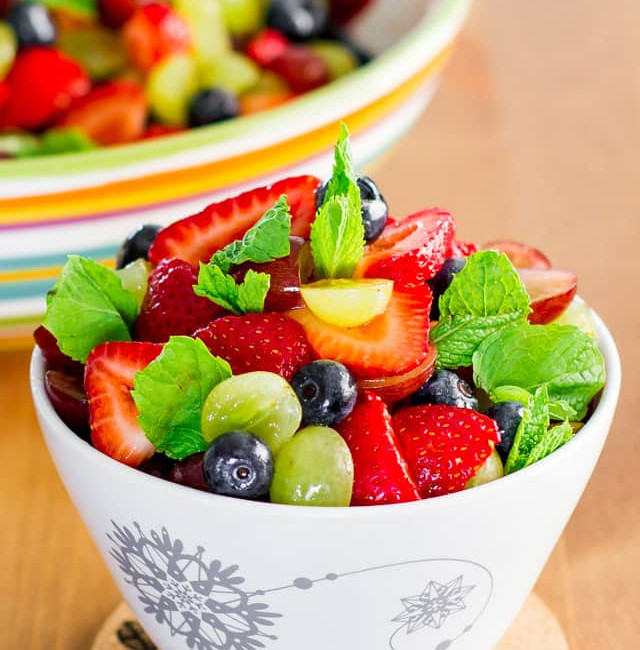 a bowl full of summer fruit salad with lemon dressing