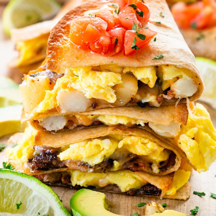 breakfast quesadilla pieces stacked and garnished with chopped tomatoes.