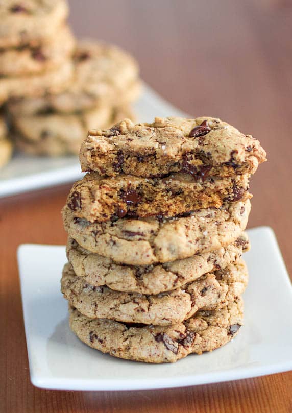 a stack of new york style chocolate chip cookies with the top cookie split in half