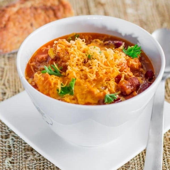 a bowl of slow cooker chicken chili topped with shredded cheese