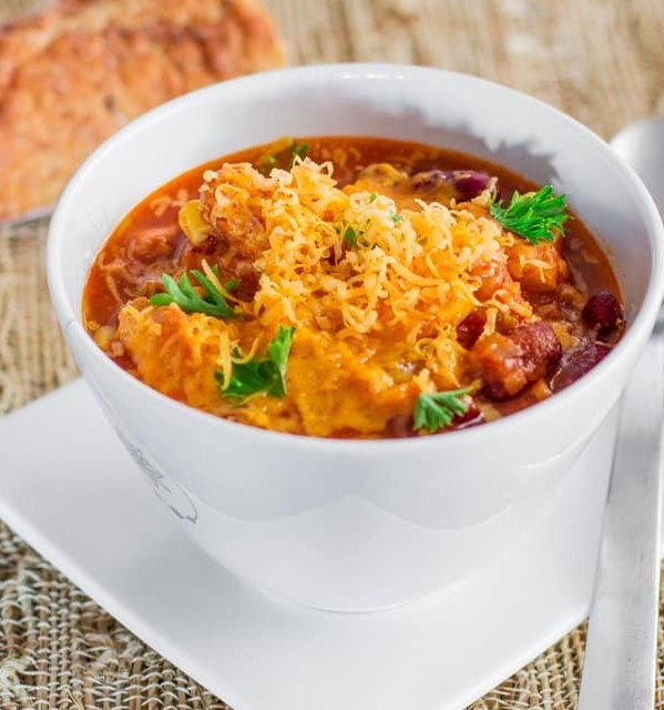 a bowl of slow cooker chicken chili topped with shredded cheese
