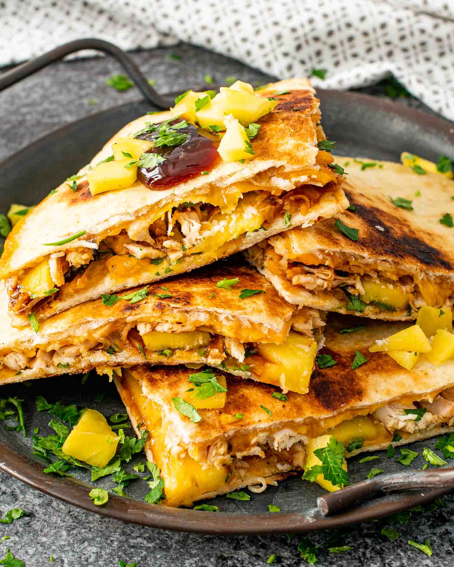 a stack of bbq chicken and mango quesadillas on a metal plate.