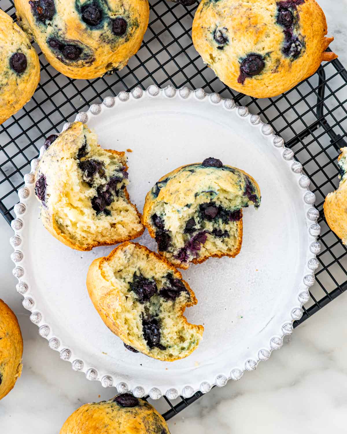overhead shot of blueberry muffin broken in half on a white plate