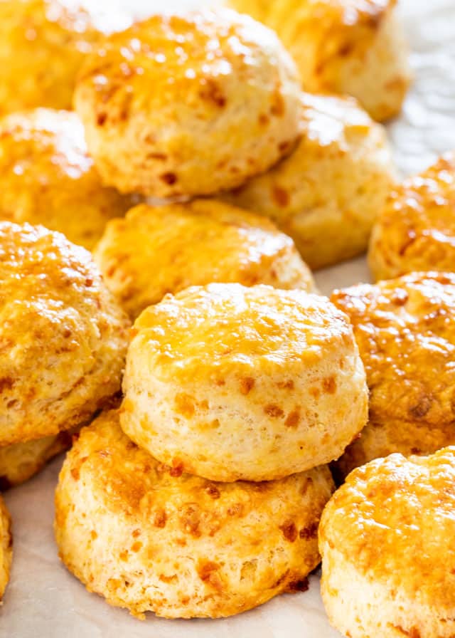 a bunch of Buttermilk Biscuits piled on top of each other on parchment paper