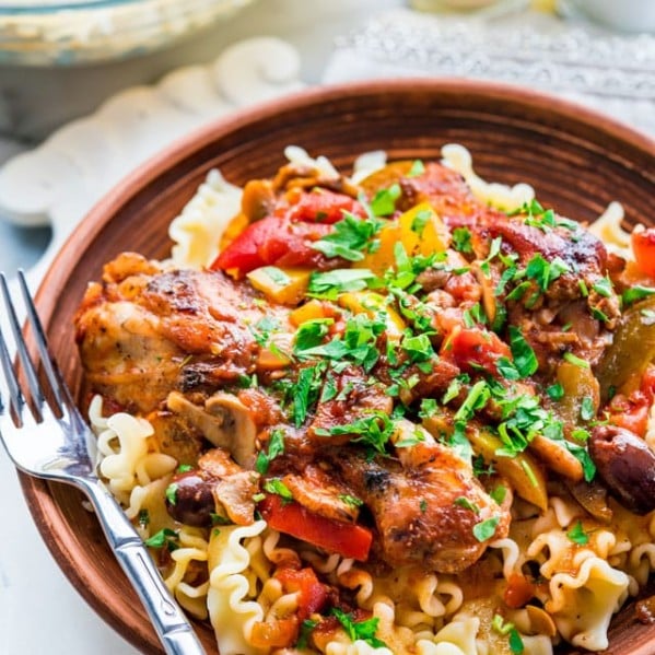 a bowl of noodles topped with chicken cacciatore