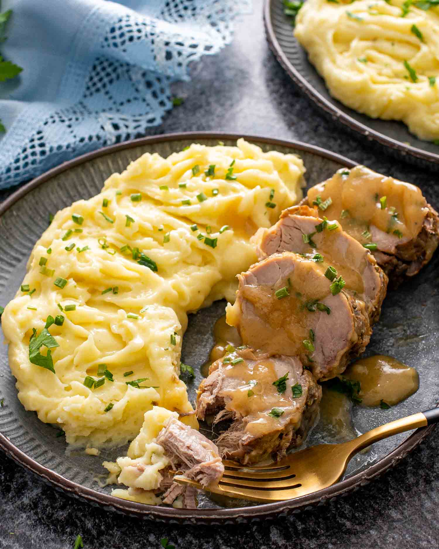 sliced cuban style pork tenderloin on a plate with mashed potatoes and gravy.