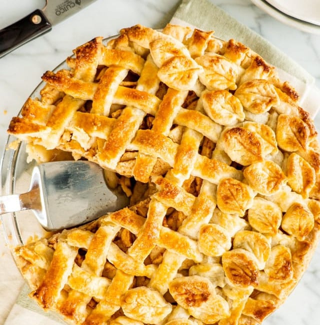 overhead shot of an apple pie with a slice missing and a pie lifter in the empty space