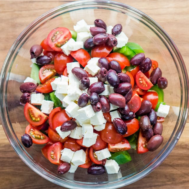 overhead shot of all the greek salad ingredients in a bowl
