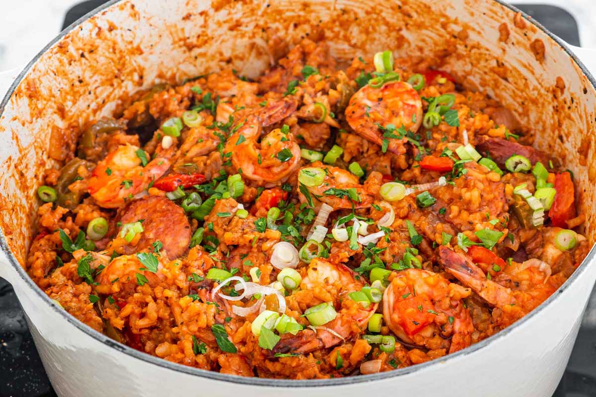 jambalaya in a dutch oven garnished with green onions and parsley