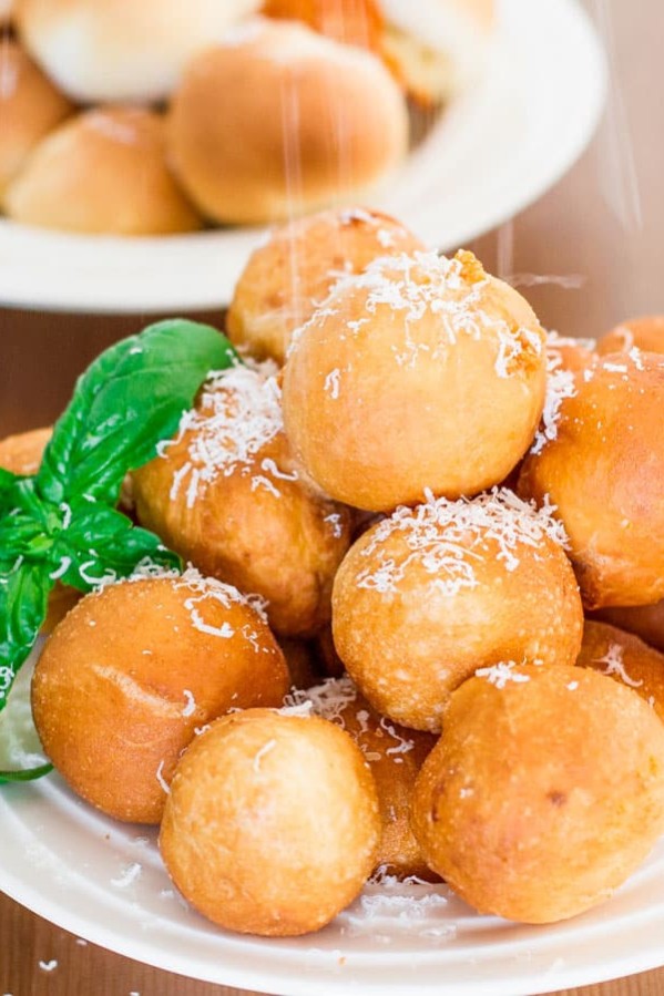 a plate of pizza balls being sprinkled with parmesan cheese