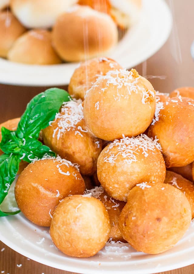 a plate of pizza balls being sprinkled with parmesan cheese