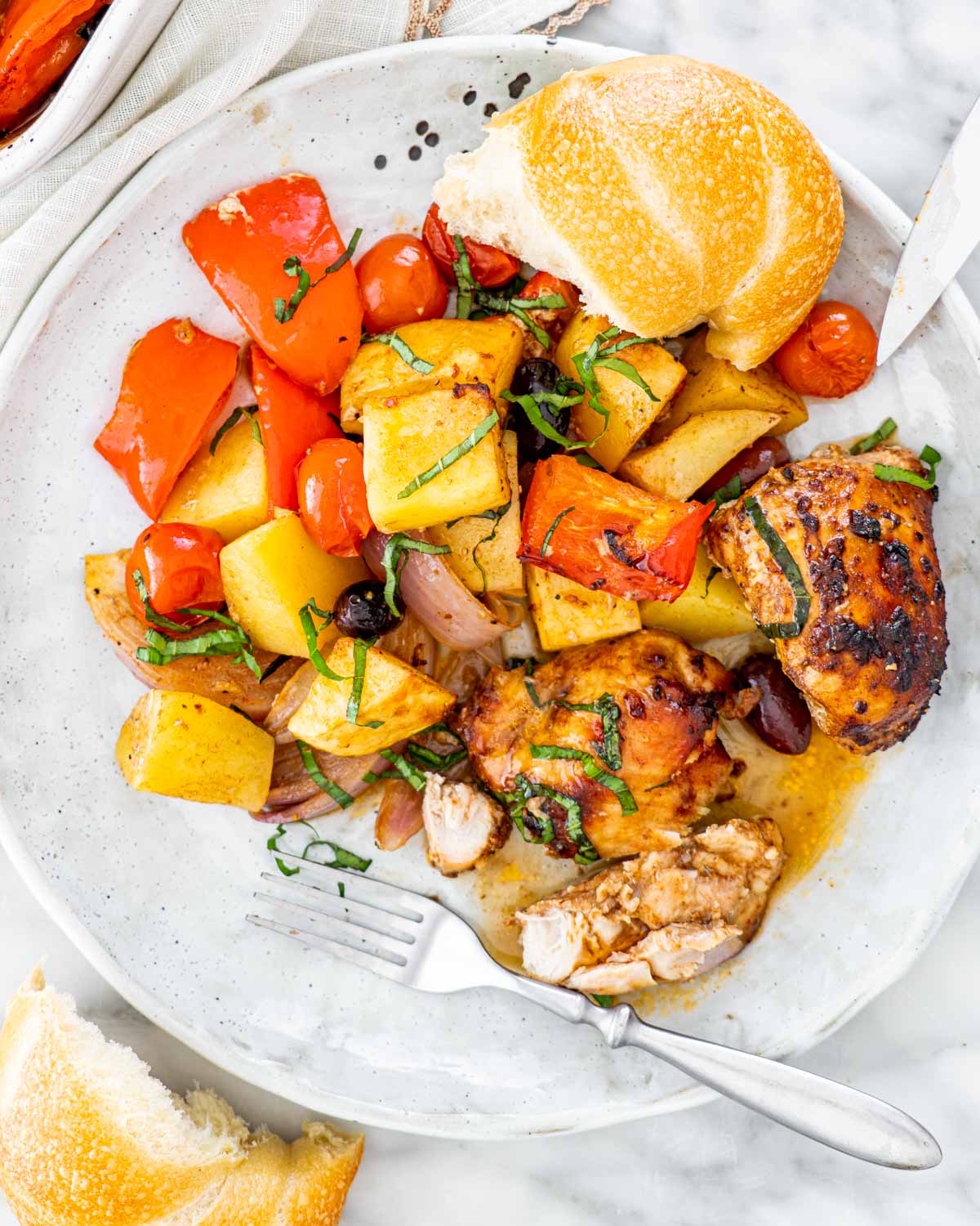 roasted chicken and vegetables on a plate with bread and a fork