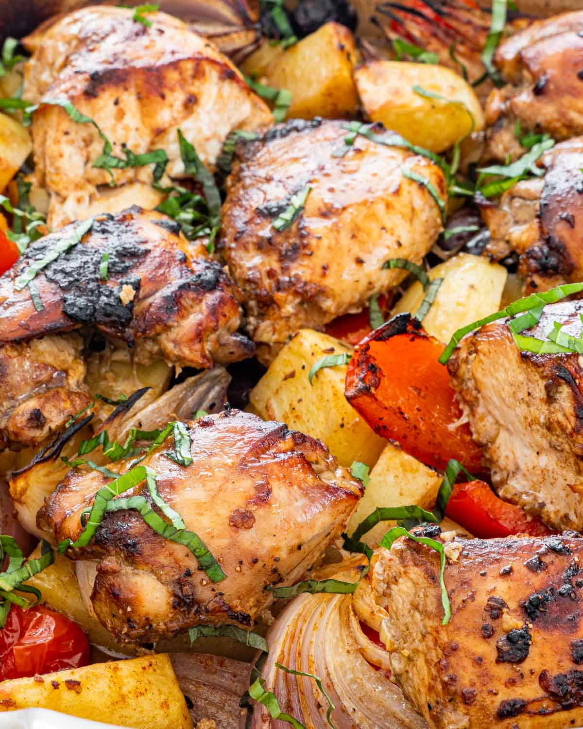 chicken and vegetables roasted in a pan and garnished with basil