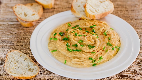 A bowl of Roasted Garlic Hummus with bread slices 