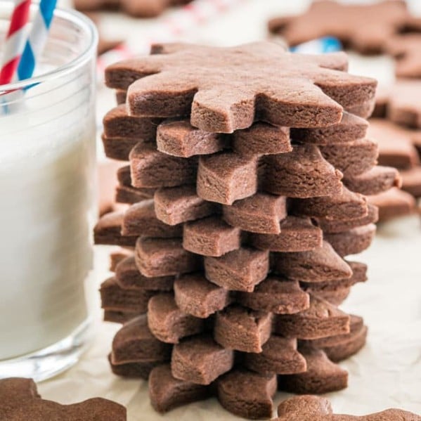 side view shot of a stack of chocolate sugar cookies stacked next to a glass of milk
