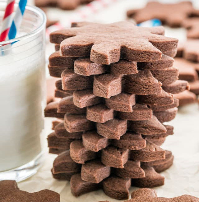 side view shot of a stack of chocolate sugar cookies stacked next to a glass of milk
