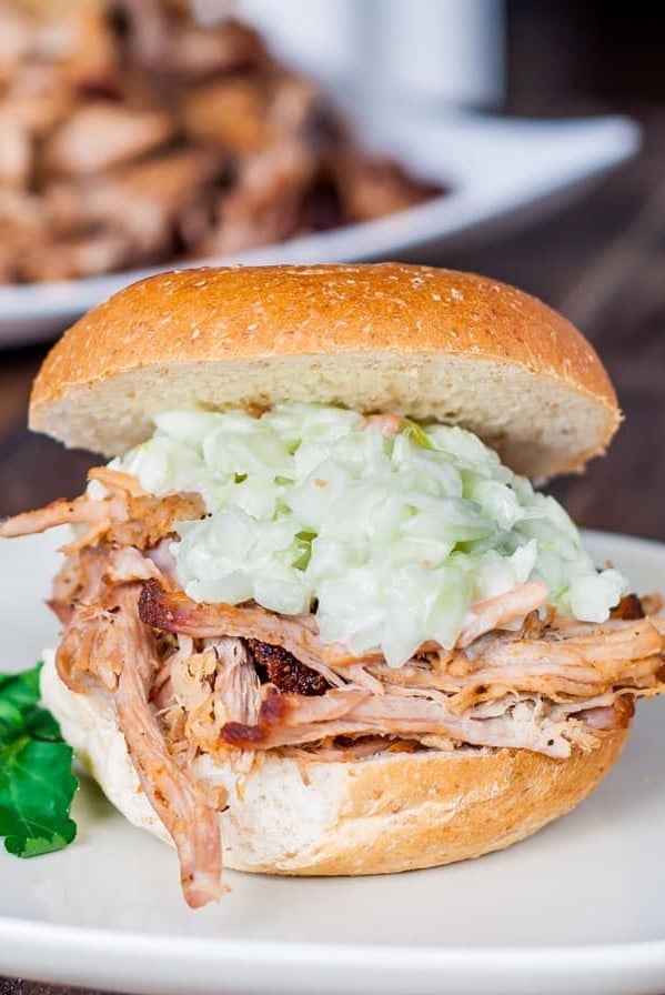 side view shot of a pulled pork sandwich topped with coleslaw on a plate