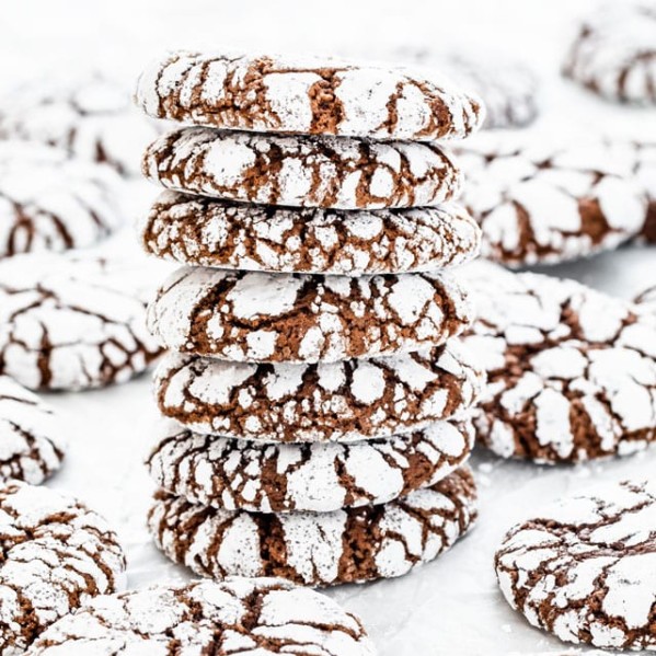 a stack of chocolate crinkle cookies surrounded by more chocolate crinkle cookies