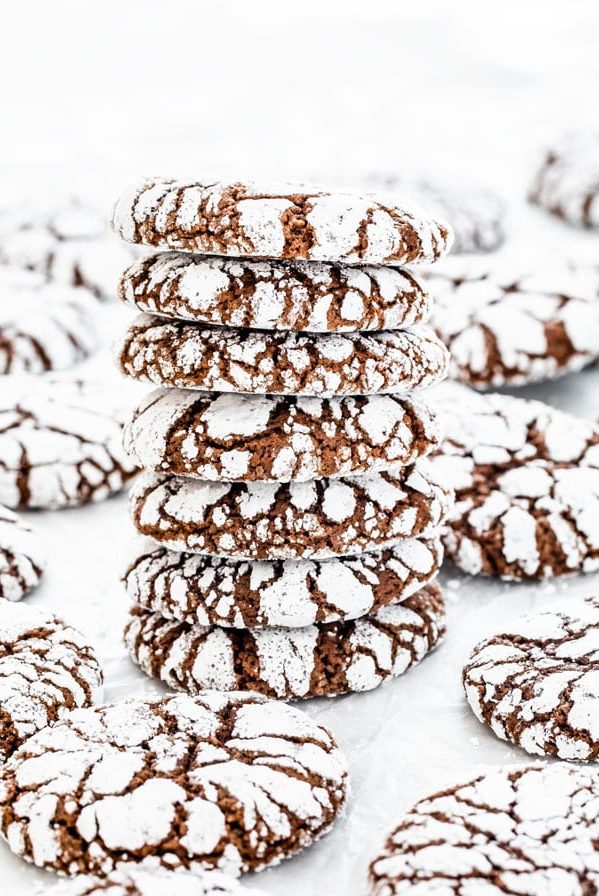 a stack of chocolate crinkle cookies surrounded by more chocolate crinkle cookies