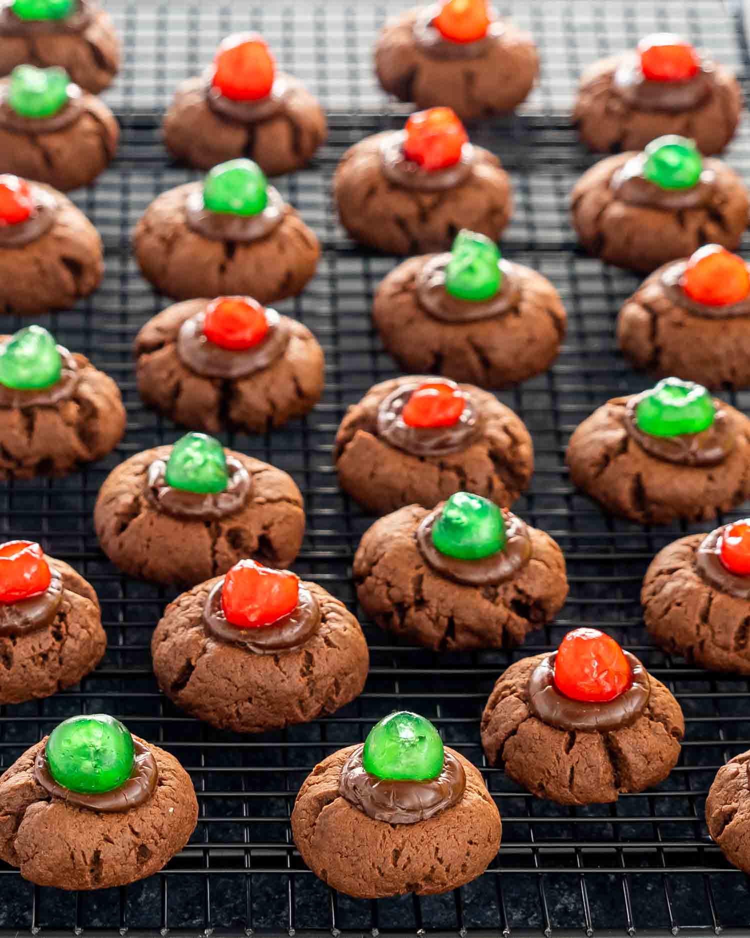 chocolate fudge cookies with maraschino cookies on a cooling rack.