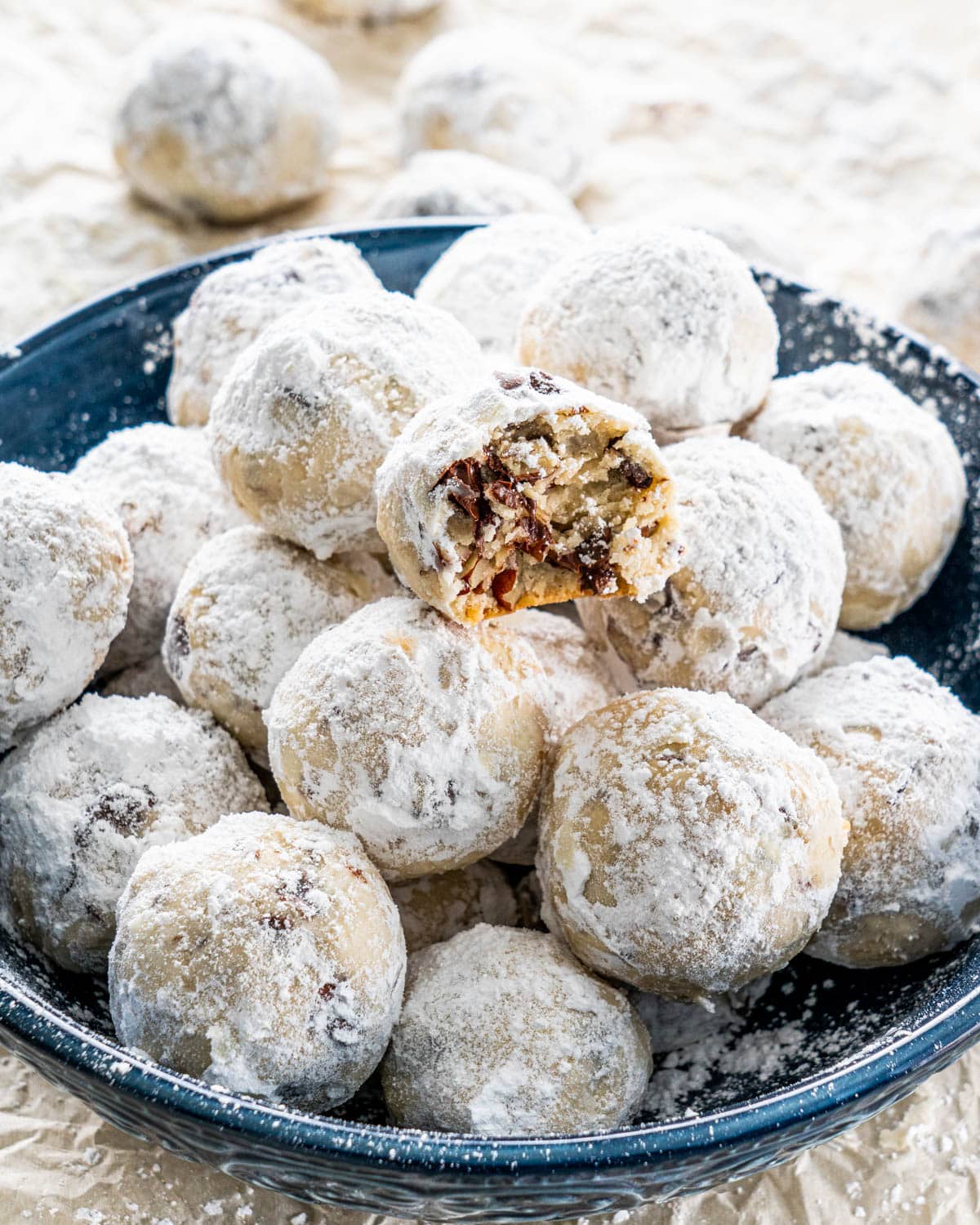 a blue bowl full of chocolate pecan snowball cookies