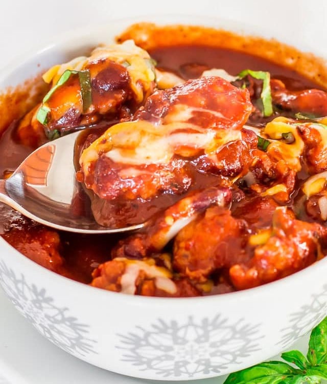 a spoon taking a bite of crockpot country sausage and bean soup