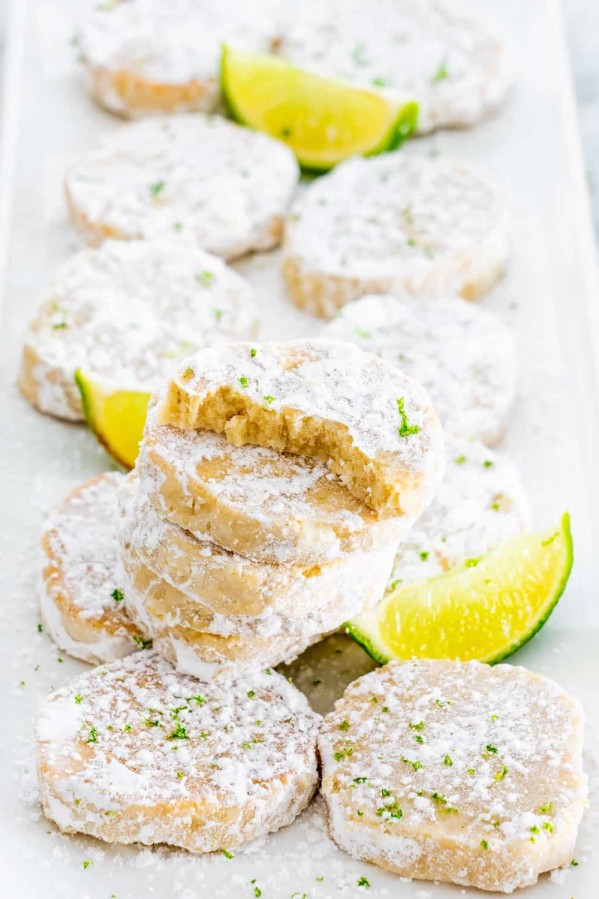 lime meltaway cookies stacked on a plate with a bite taken out of one