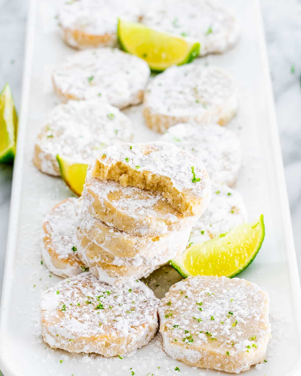 lime meltaway cookies on a white plate garnished with lime wedges