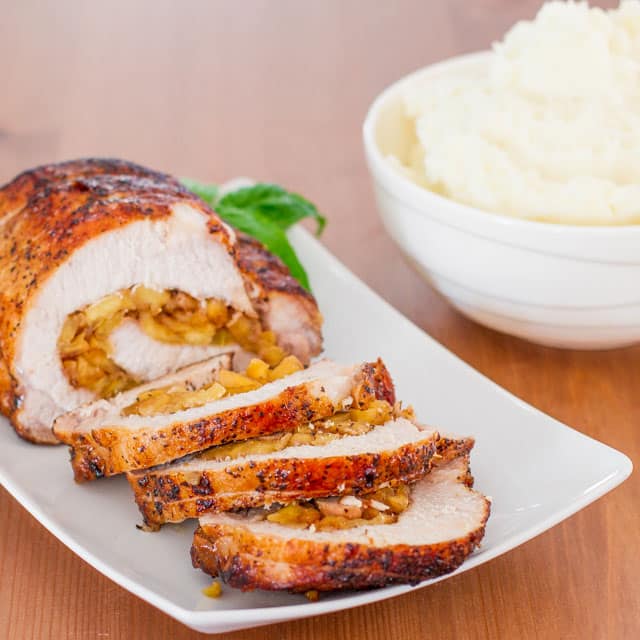 Caramelized Pork Loin stuffed with caramelized apples sliced on a white plate