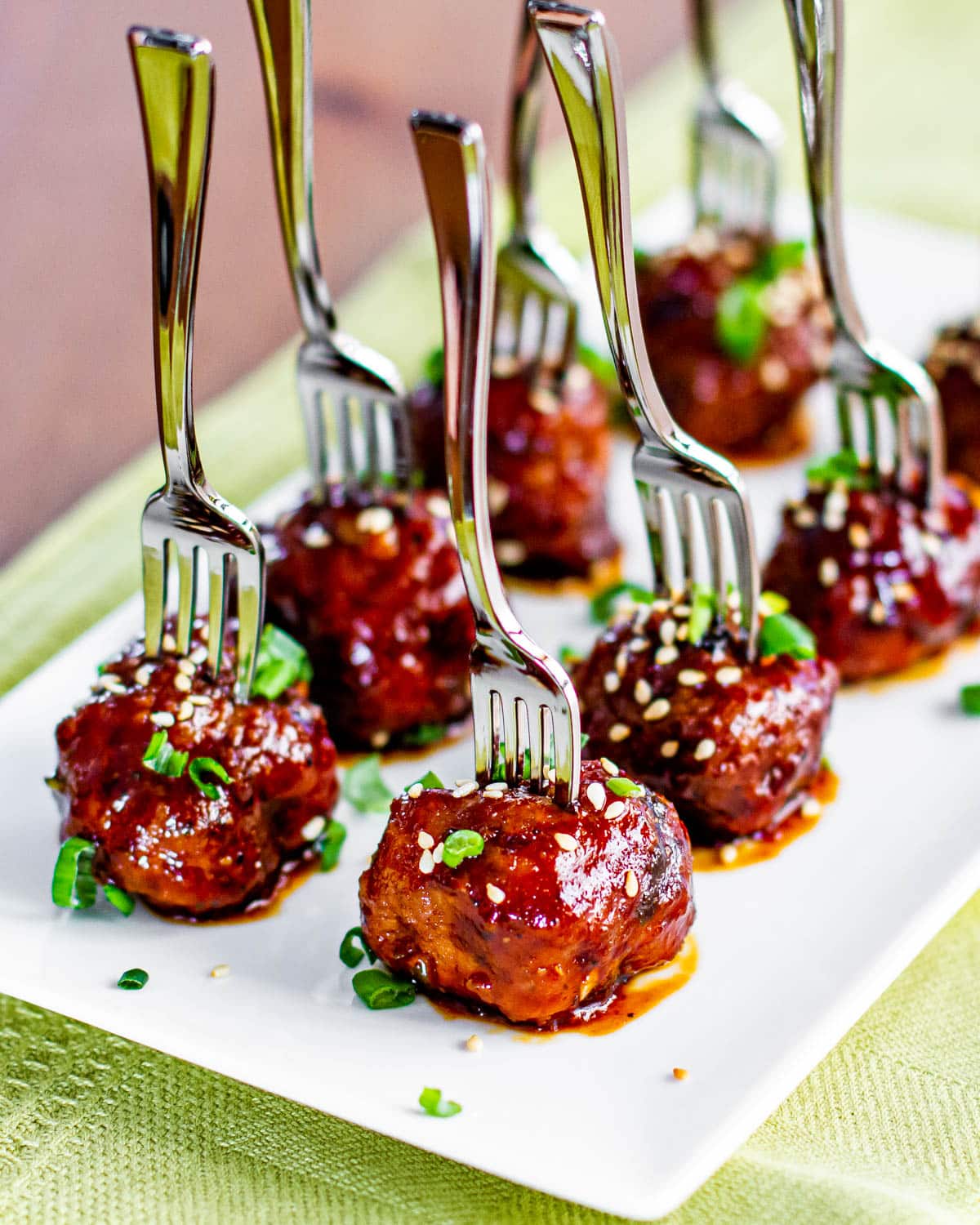 crockpot asian meatballs on a plate with forks stuck in the tops