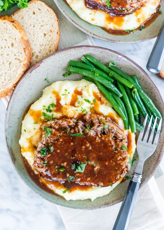 a slice of meatloaf over mashed potatoes and green beans