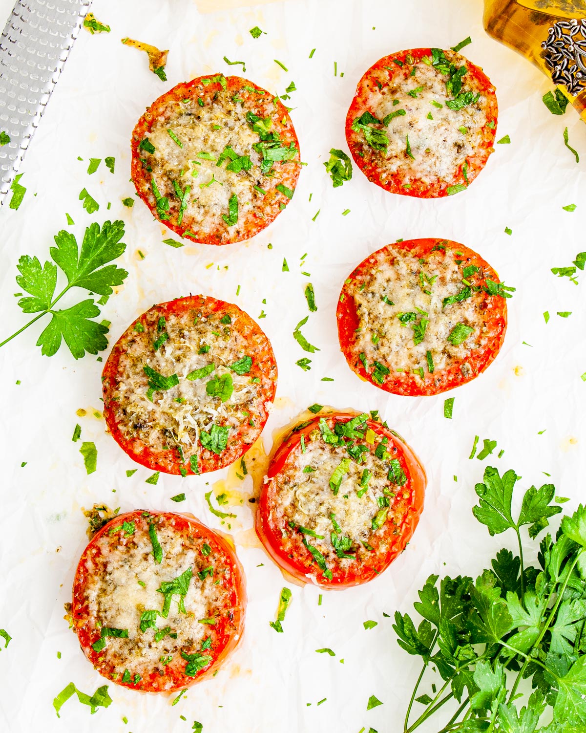 overhead shot of 6 sliced of baked parmesan tomatoes garnished with parsley