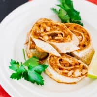 chicken enchilada roll ups stacked on a plate